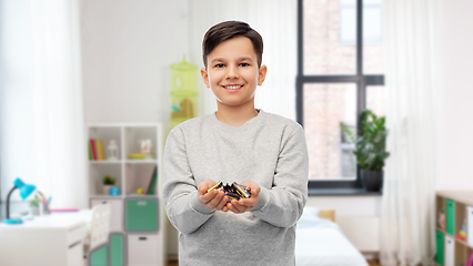 Image showing happy boy holding pile of batteries at home