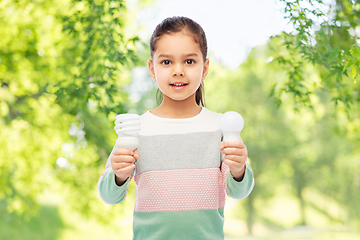 Image showing smiling girl comparing different light bulbs