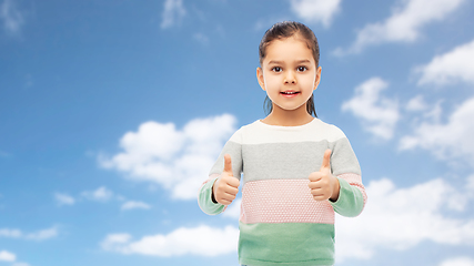 Image showing happy girl showing thumbs up over sky and clouds