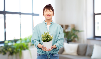 Image showing happy smiling asian woman holding flower in pot