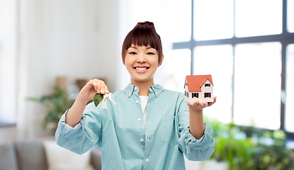 Image showing smiling asian woman holding house model and keys