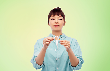 Image showing asian woman braking cigarette over green