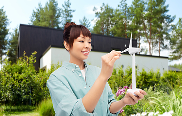 Image showing smiling young asian woman with toy wind turbine