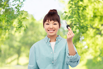 Image showing happy asian woman holding car key with green leaf