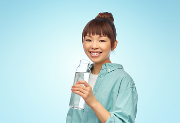 Image showing happy asian woman holding glass bottle with water