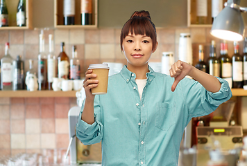 Image showing asian woman with coffee showing thumbs down at bar