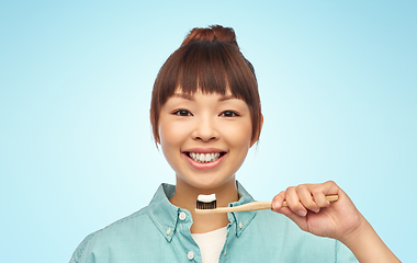 Image showing asian woman with toothpaste on wooden toothbrush