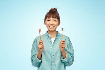 Image showing asian woman with wooden and plastic toothbrushes