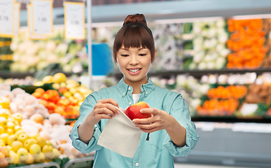 Image showing happy woman putting apple into reusable bag