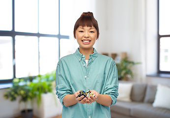 Image showing smiling young asian woman with alkaline batteries