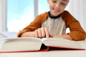 Image showing smiling student boy writing to notebook at home