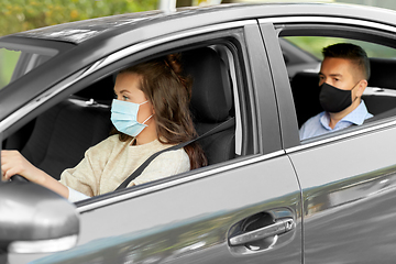 Image showing female driver in mask driving car with passenger