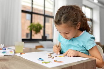 Image showing little girl painting wooden items at home