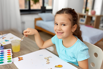 Image showing little girl painting wooden items at home