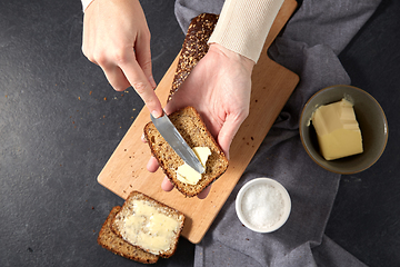 Image showing female baker spreading butter on homemade bread