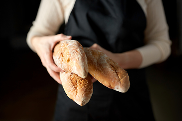Image showing close up of female baker holding baguette bread