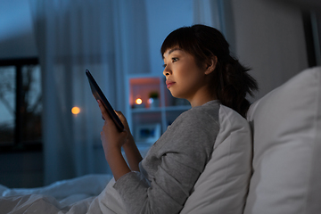 Image showing asian woman with tablet pc in bed at home at night