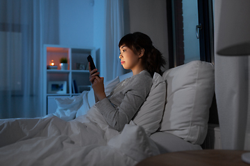 Image showing asian woman with smartphone in bed at night