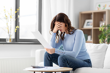 Image showing stressed woman with papers and calculator at home