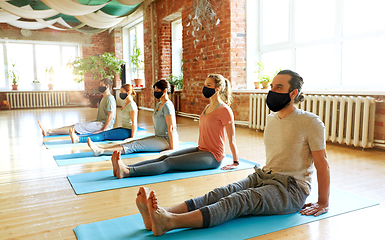 Image showing group of people in masks doing yoga at studio