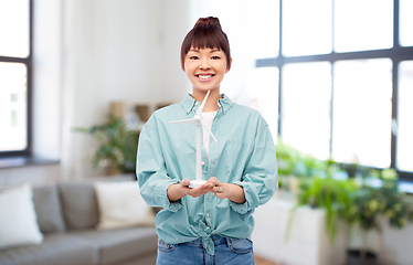 Image showing smiling young asian woman with toy wind turbine