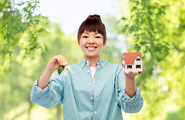 Image showing smiling asian woman holding house model and keys