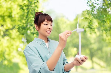 Image showing smiling young asian woman with toy wind turbine