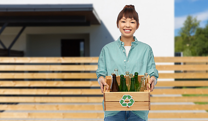 Image showing smiling young asian woman sorting glass waste