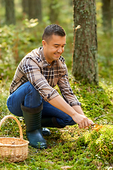 Image showing happy man with basket picking mushrooms in forest