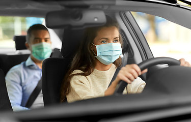 Image showing female driver in mask driving car with passenger