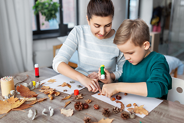 Image showing mother and son making pictures of autumn leaves