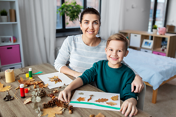 Image showing mother and son making pictures of autumn leaves