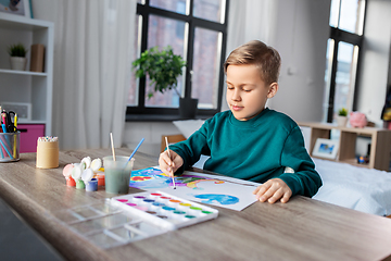 Image showing boy with colors and brush drawing picture at home