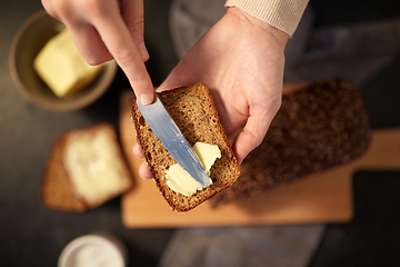 Image showing female baker spreading butter on homemade bread