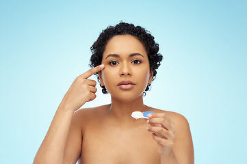 Image showing african american woman putting on contact lenses