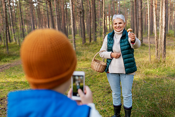 Image showing grandson photographing grandmother with mushroom