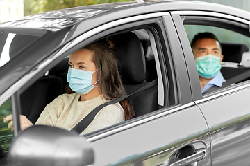 Image showing female driver in mask driving car with passenger