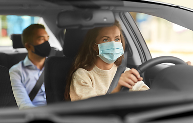 Image showing female driver in mask driving car with passenger