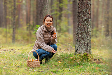 Image showing young woman picking mushrooms in autumn forest