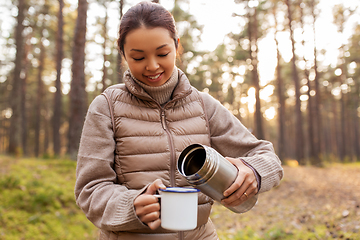 Image showing asian woman with thermos drinking tea in forest