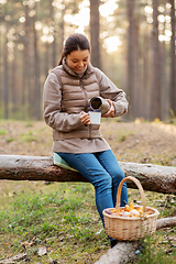 Image showing asian woman with thermos drinking tea in forest