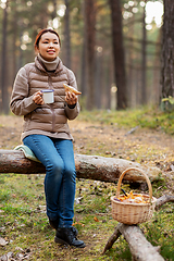 Image showing woman with mushrooms drinks tea and eats in forest