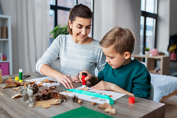 Image showing mother and son making pictures of autumn leaves