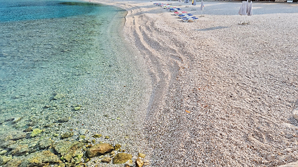 Image showing Beautiful shore of the Adriatic Sea. Bay view with beach and deck chairs. Sunrise