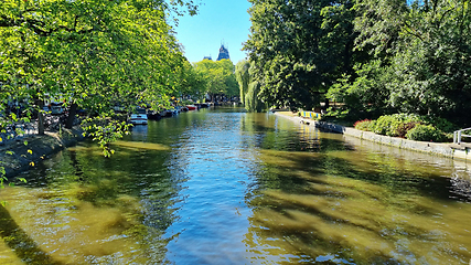 Image showing Channel in Amsterdam Netherlands. Big trees near river Amstel landmark. Old European city summer landscape