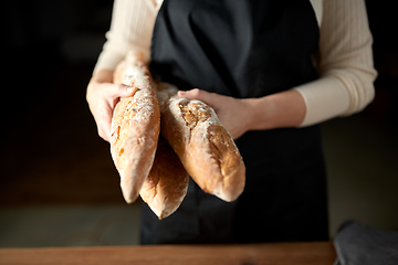 Image showing close up of female baker holding baguette bread