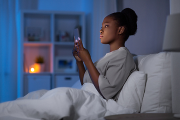 Image showing woman with smartphone in bed at home at night