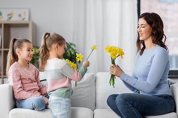 Image showing daughters giving daffodil flowers to happy mother