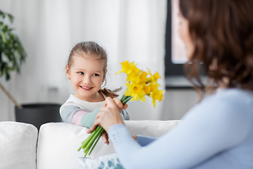 Image showing happy daughter giving daffodil flowers to mother