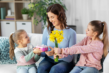 Image showing daughters giving flowers and gift to happy mother